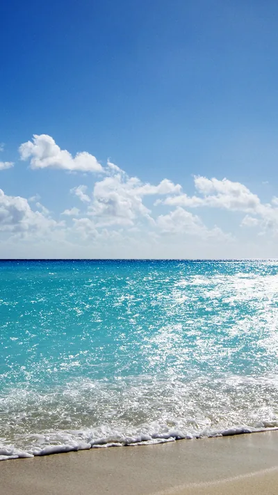 Open water glitters from the horizon down to a sliver of sand, and the tall empty sky above leaves the whole top half for the clock.