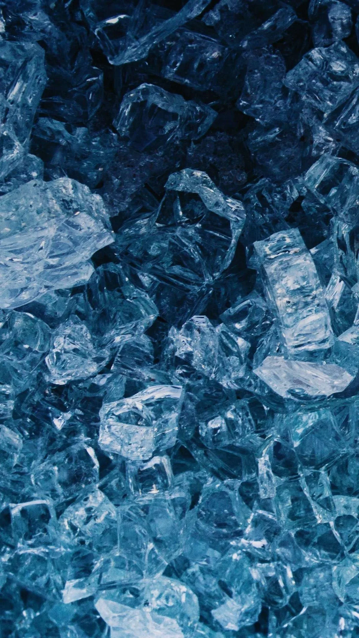 Chunks of shattered blue glass pack the frame edge to edge, brightest through the middle band, with deeper navy shadow settling along the top and bottom edges.