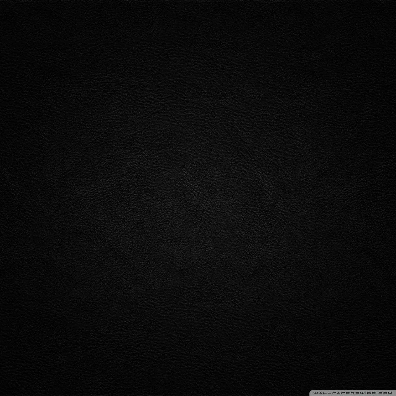 Tight pebbled leather fills the square frame, the grain catching a faint sheen toward the upper left and sinking to flat black at the edges.