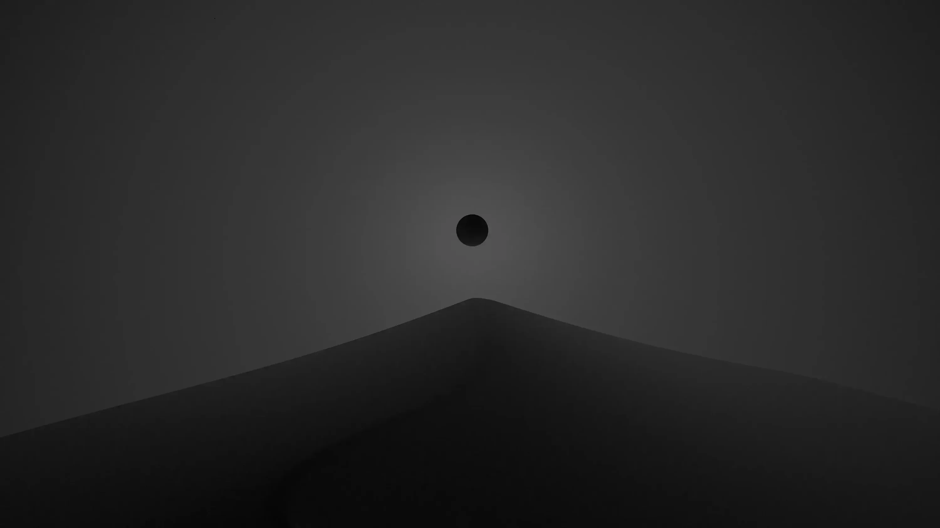 A small black disc hangs above a smooth grey ridge, the sky lightening only where the slope meets it.