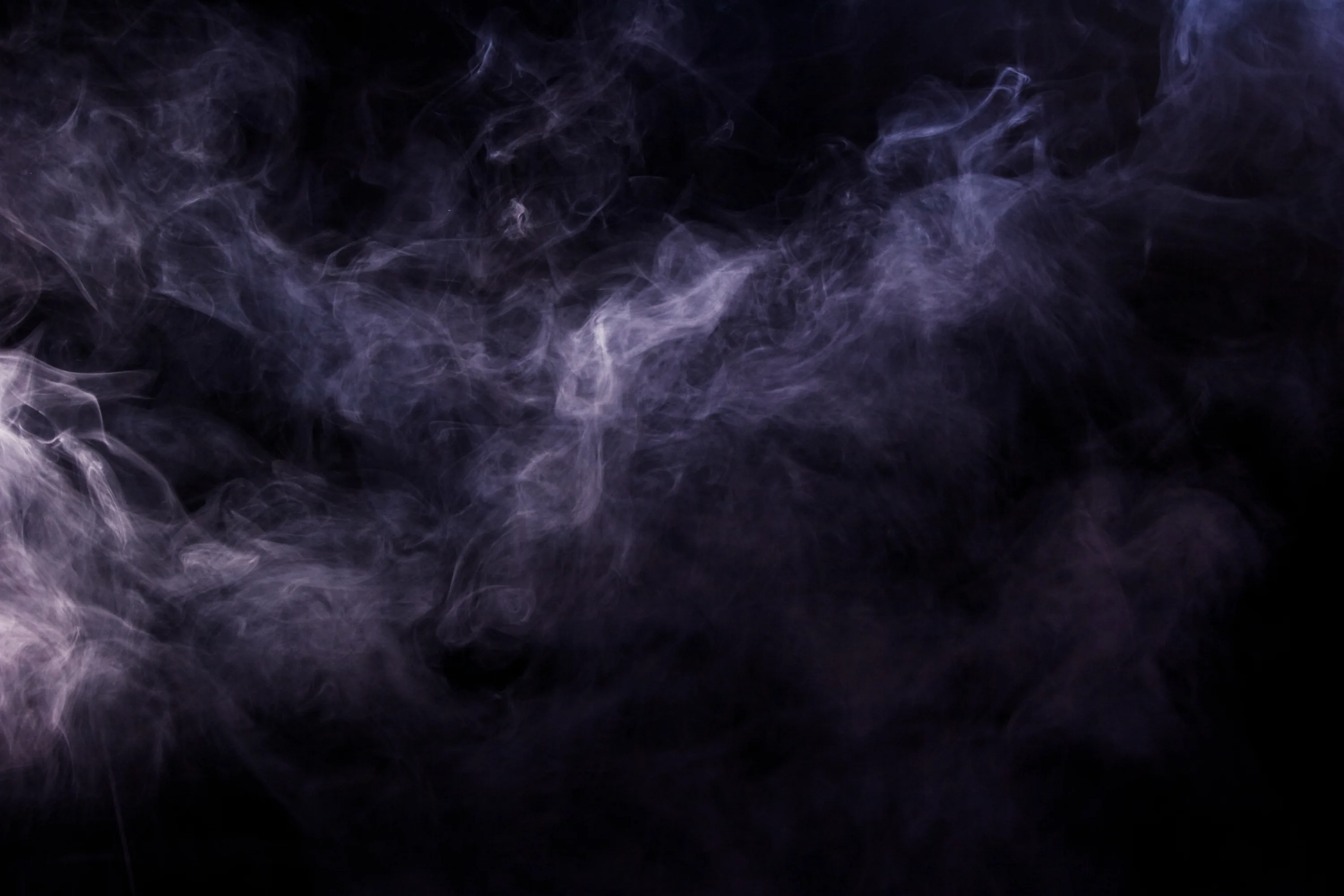 Low violet-grey haze hangs across the frame like storm cloud at night, thickest along the left edge, with true black pooling underneath for OLED.
