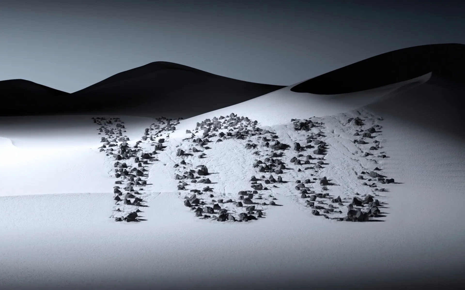Dark stones laid out to spell YOU on a bright sand slope, black dunes rolling behind under a flat grey sky.