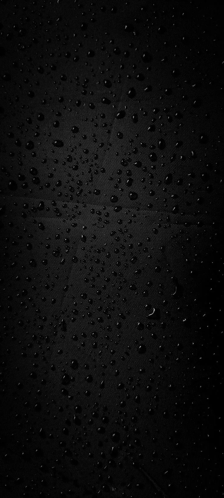 Rain beads cling to a sheet of black glass, clustered in the middle where a faint backlight catches their edges.
