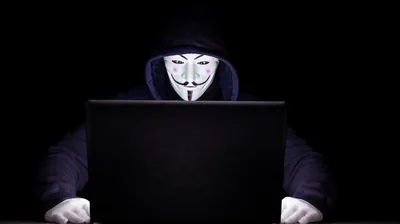 Masked Hacker Behind a Laptop HD Wallpaper