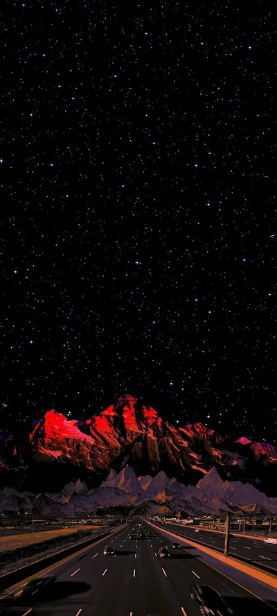 Red Lit Mountain Above a Night Highway HD Phone Wallpaper