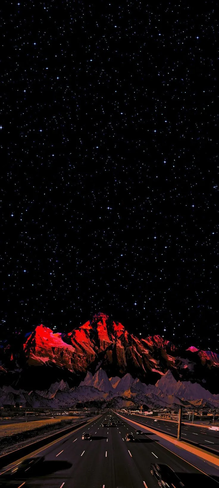 A rocky ridge burns deep red under a thick star field while a lit highway runs straight out of the bottom of the frame.