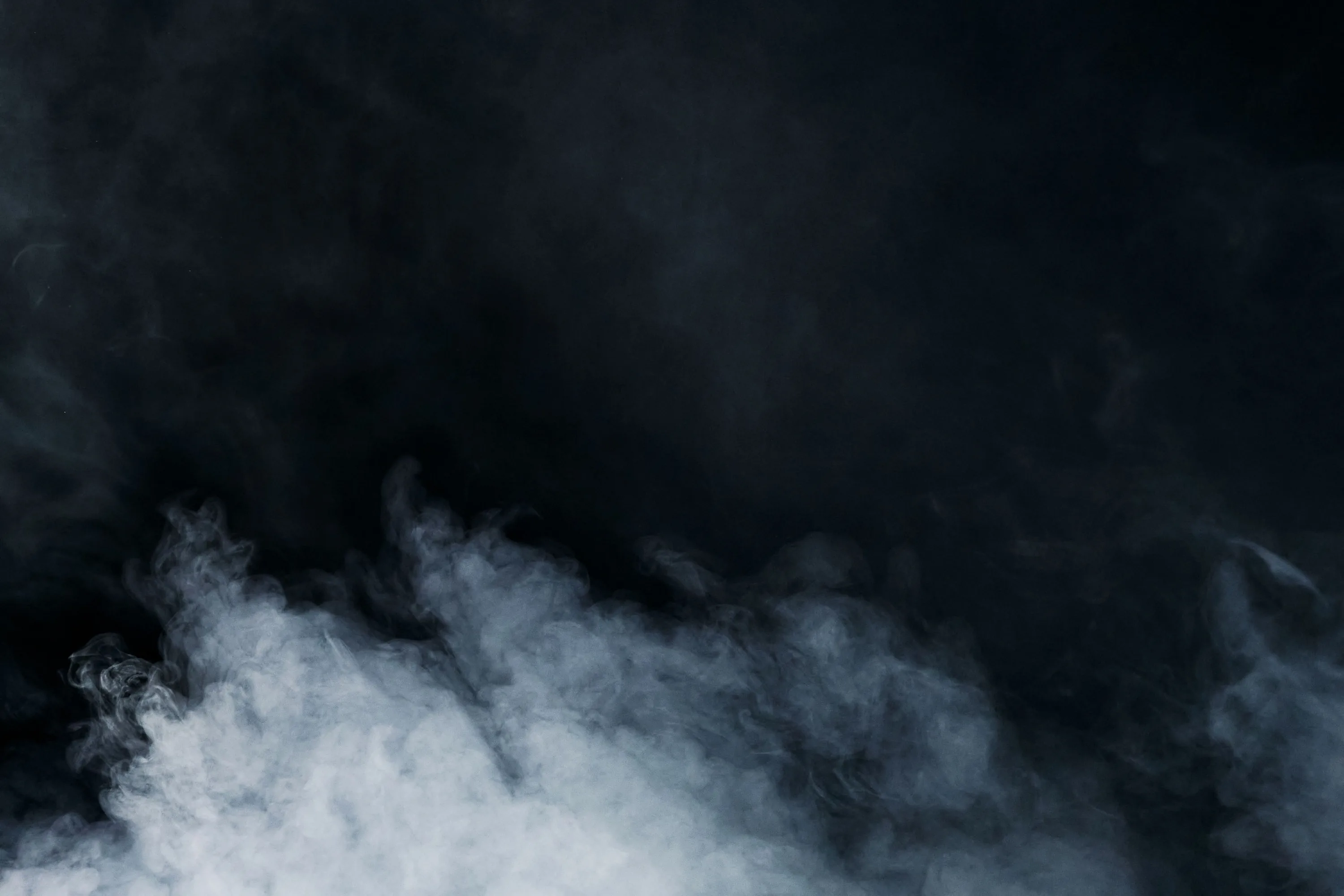 A textured cloud rolls low along the bottom edge like ground fog, lit from the front, while the upper half stays a deep blue-black.