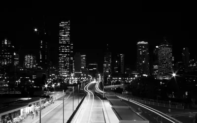 Freeway Light Trails Below a City Skyline HD Wallpaper