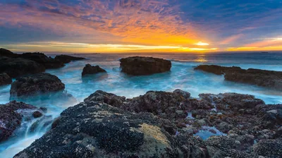 Amber Horizon Behind Mist-Blurred Rocks HD Wallpaper