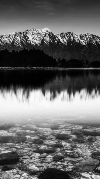 Snowy Peaks Above a Clear Stone Lake HD Phone Wallpaper