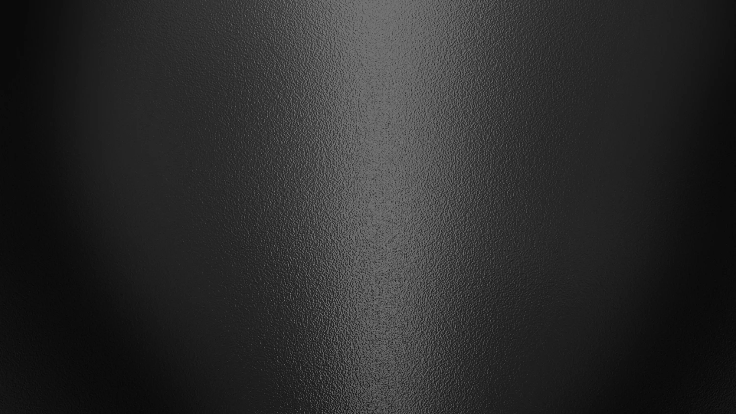 A faint column of light falls down the centre of finely grained matte black, both side edges staying dark for OLED screens.