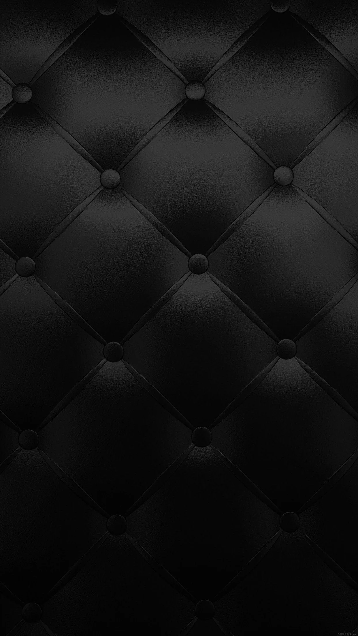 Diamond-quilted leather with a button sunk at every join, the padding catching a dim light so each panel bulges slightly.