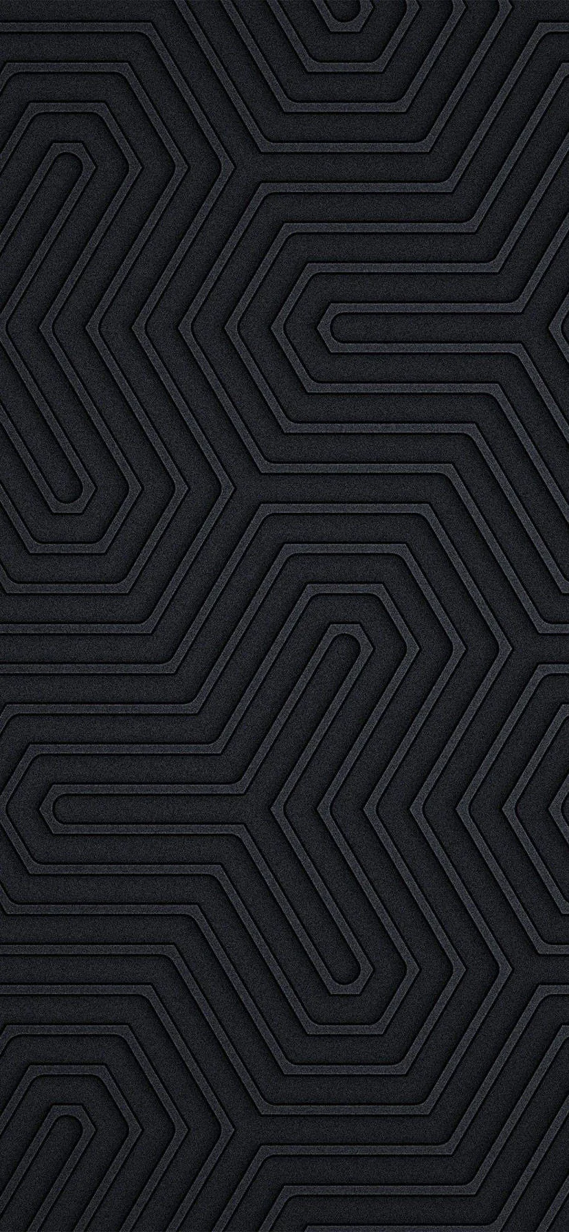 Raised hexagonal maze lines wind across matte black, catching just enough light along their edges to give the surface depth.