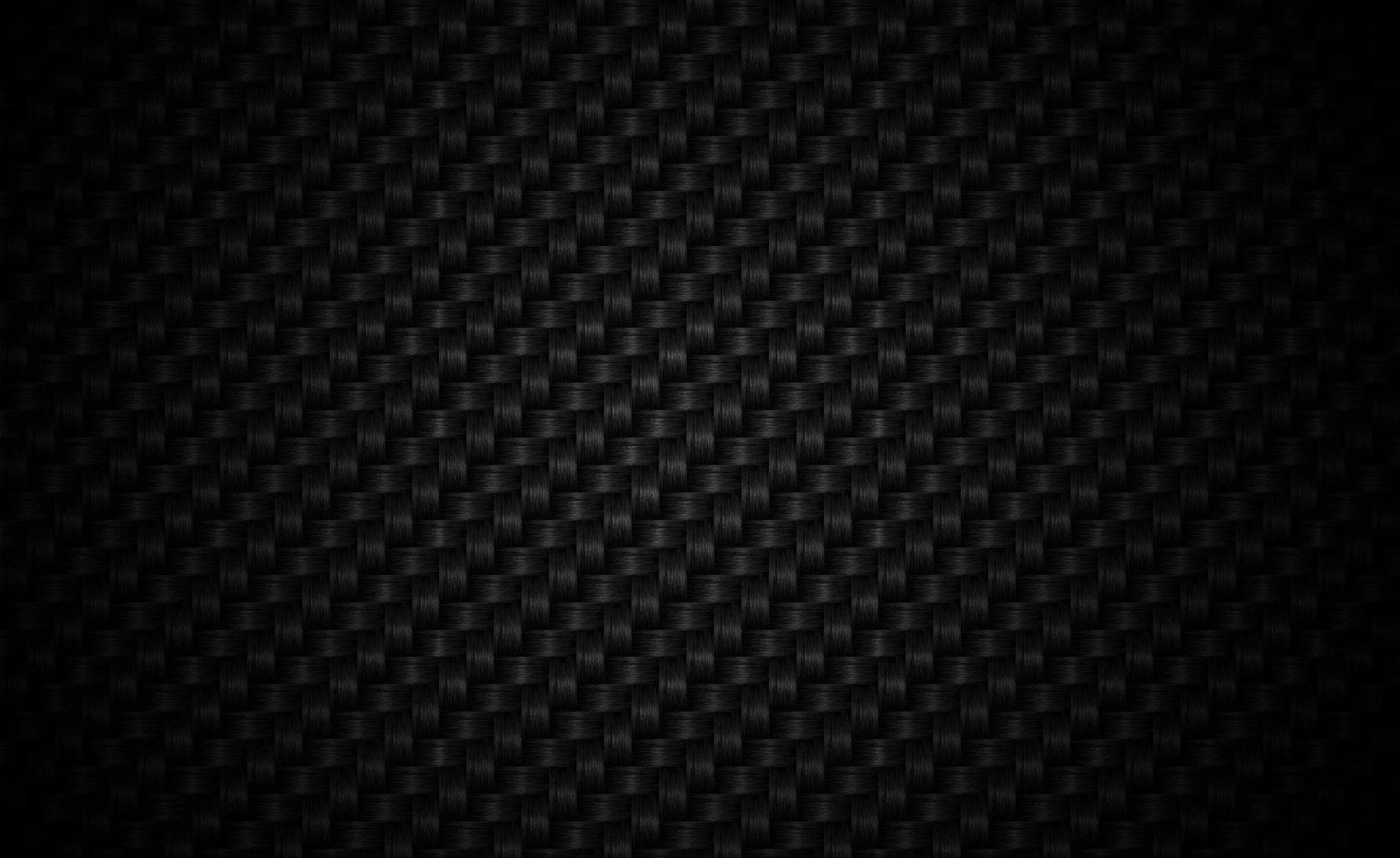 A close basket weave runs edge to edge in matte black, lifted slightly at the centre and sinking to solid shadow in every corner.