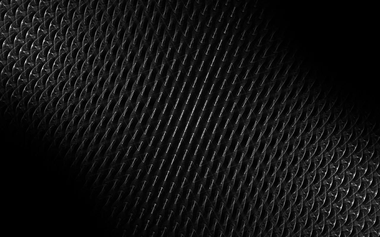 A rubber or leather surface stamped with a diamond weave curves through the frame, the light raking in from the right and the left corner in full shadow.
