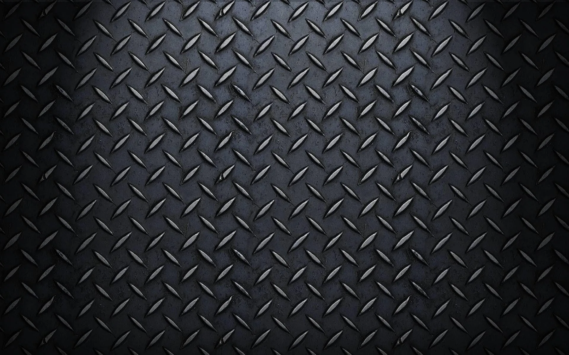 Rows of raised tread marks on dark diamond plate steel, lit from the top centre so the upper half shines while both lower corners go black.
