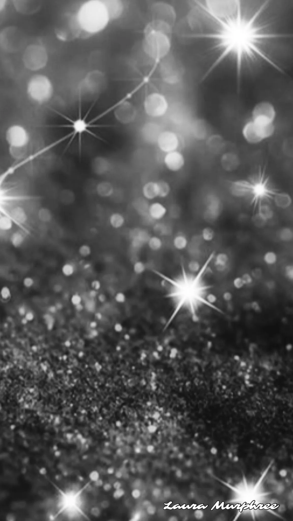 Four-point star flares scattered across defocused grey bokeh, the sharpest glitter grain sitting in the lower third, everything rendered in black and white.