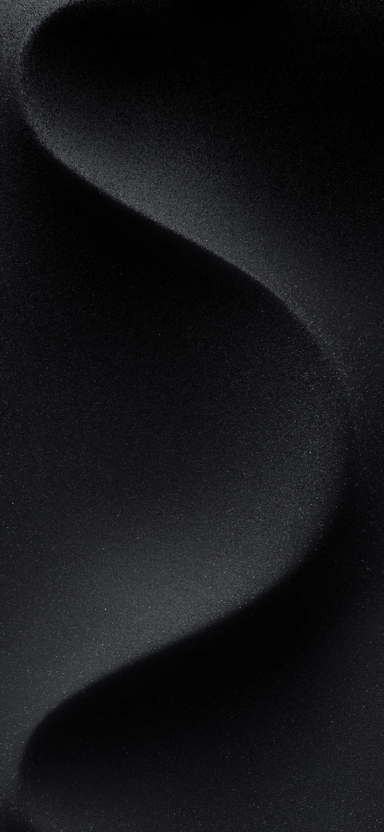 A single S-curve rolls through matte black fabric, the weave just visible where a soft light grazes the top of the ridge.