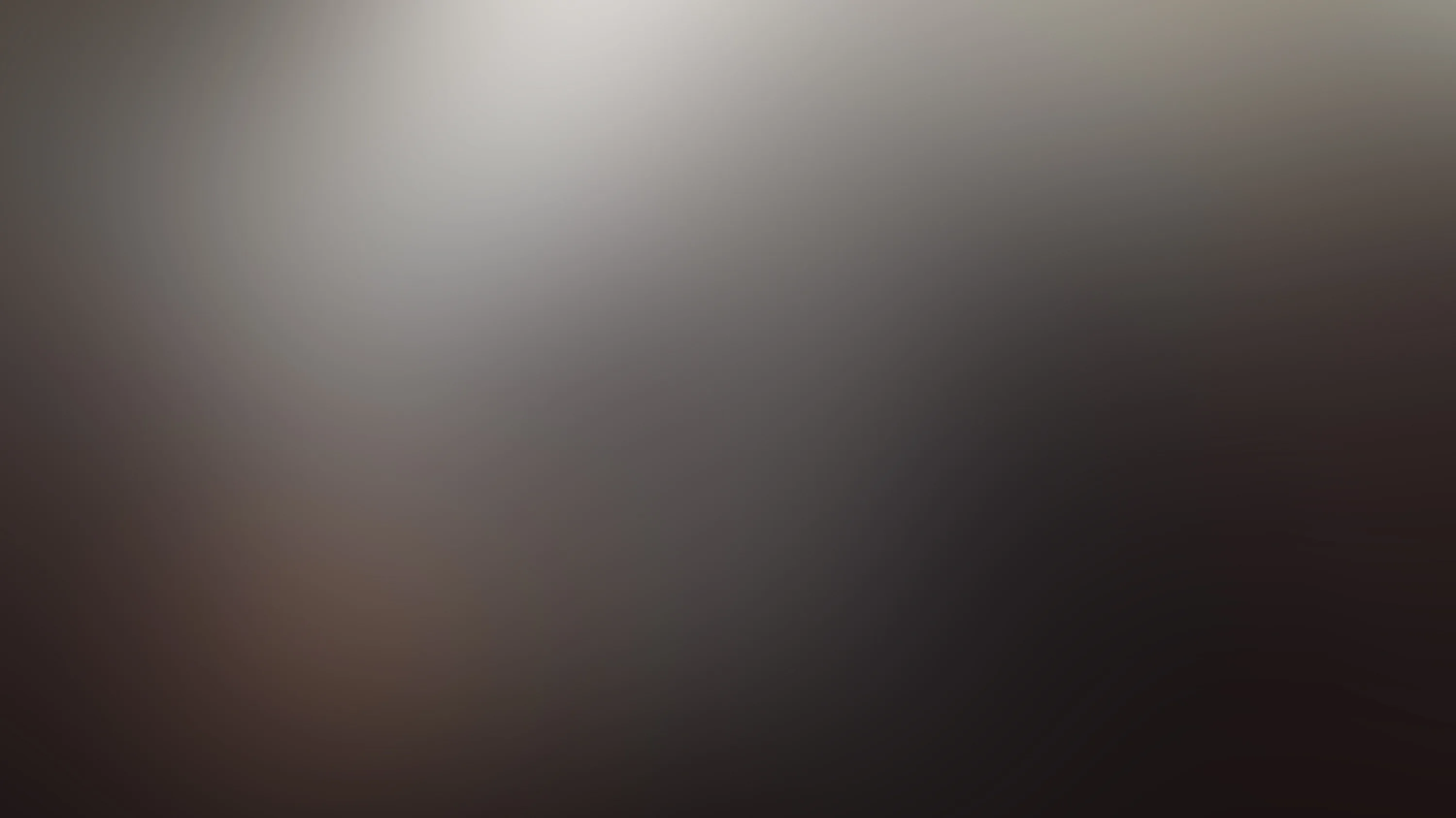 An out-of-focus wash with pale light in the upper left bleeding into warm brown and then black toward the bottom right corner.