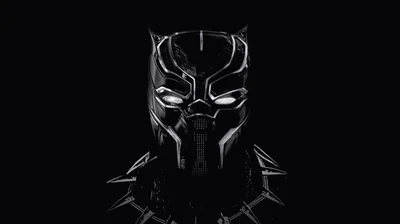 The Black Panther mask gleams out of darkness above a silver claw necklace, highlights tracing its ridges while both sides fall away to true black.