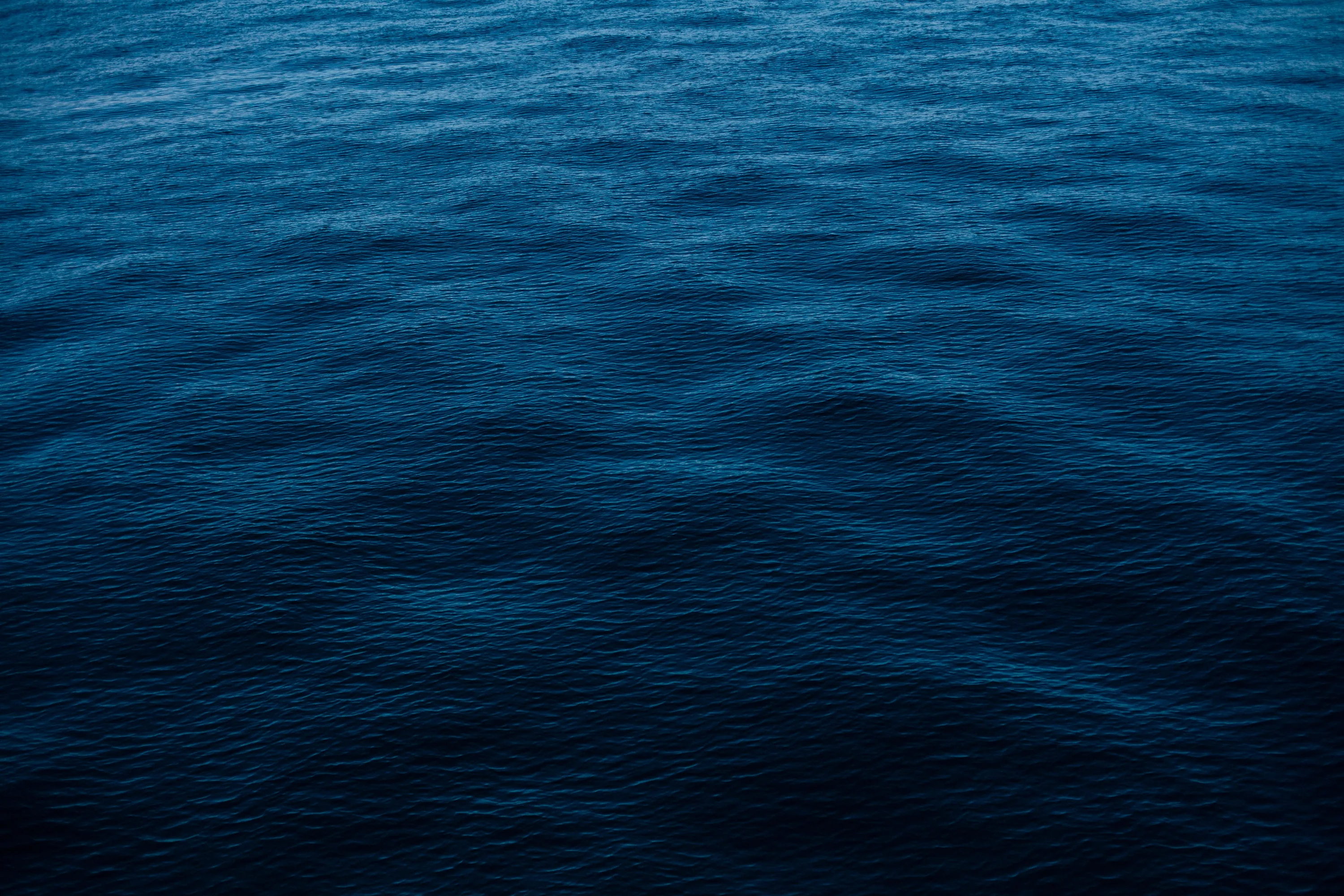 Gentle swells cross an empty stretch of prussian-blue ocean, evenly textured from edge to edge so a full grid of icons sits comfortably anywhere.