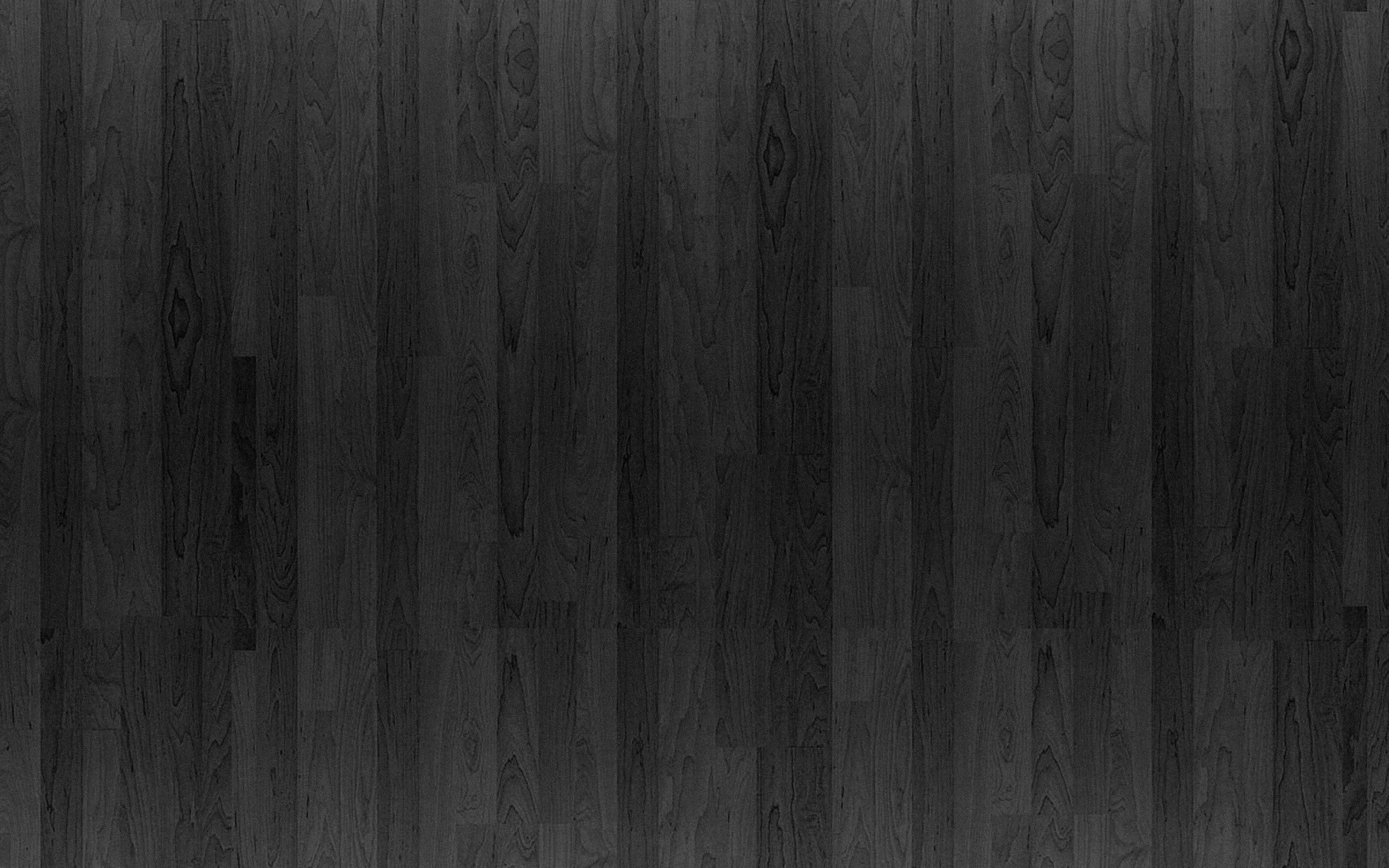Slim grey-black floorboards with tight straight grain, one flame-shaped figure above centre-left, the left and right edges dimming slightly toward the frame.