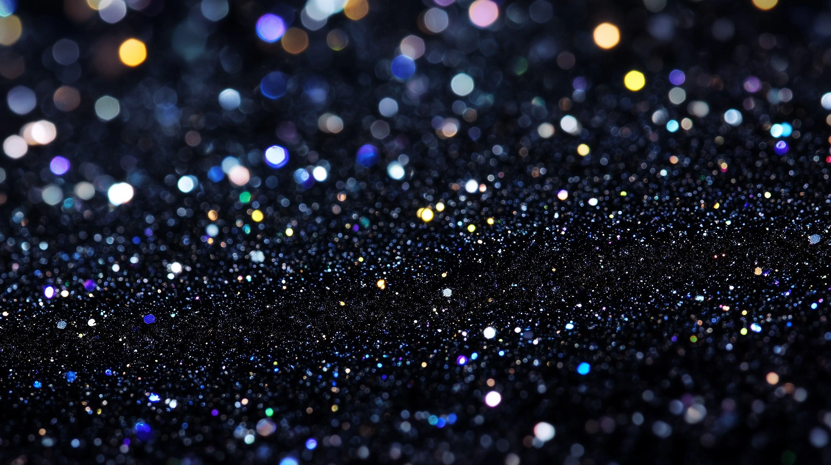 A navy-black glitter ridge runs in sharp focus through the middle, out-of-focus dots of gold, violet and blue crowding along the top edge.