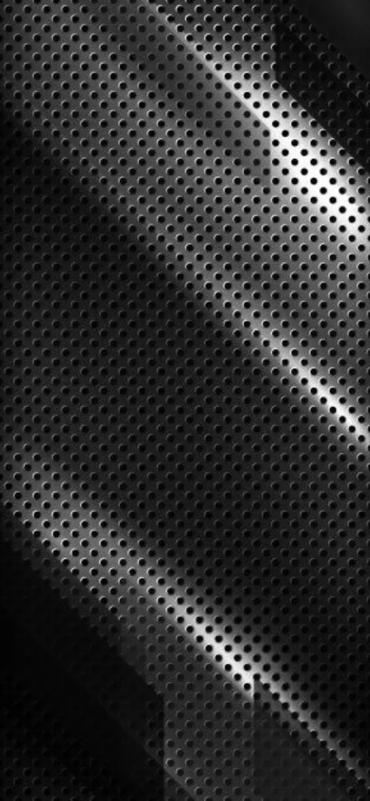 A sheet of tiny punched holes fills this tall frame, diagonal highlights gliding across its middle while all four corners hold deeper shadow.