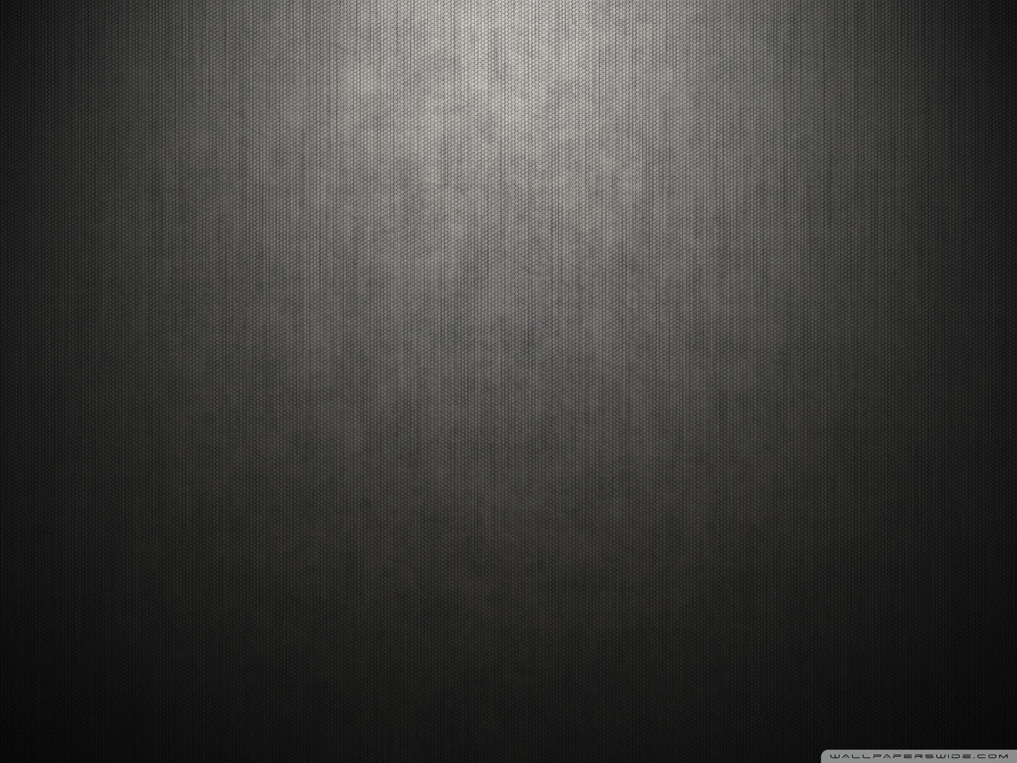 A brushed grey backdrop lit from above, the beam widening down the centre while the lower corners fall away to near black.