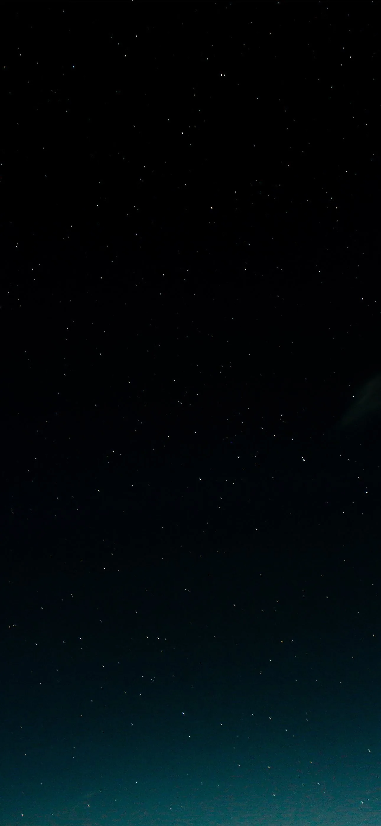 Scattered stars across near-black at the top, the sky warming into deep teal toward the bottom edge with no horizon in sight.