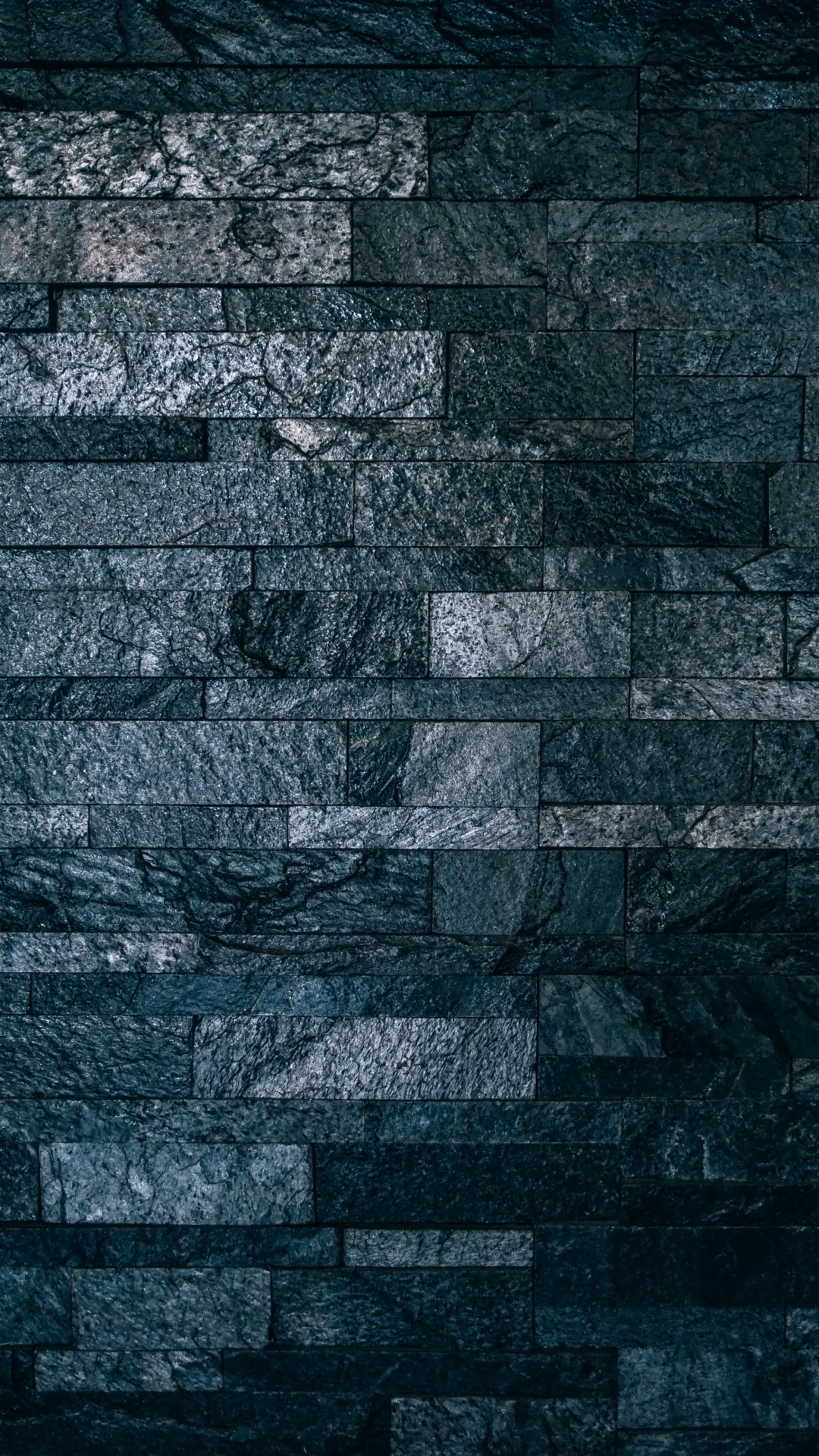 Narrow stone strips run in tight horizontal rows up a tall frame, the blue-grey faces rough enough to catch light along every ridge.