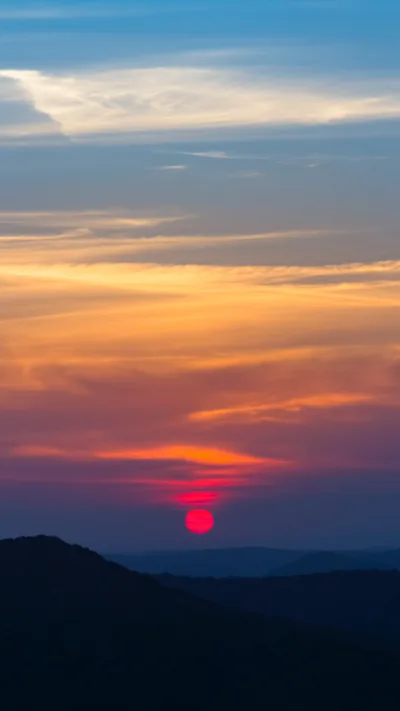 Red Sun Setting Behind Dark Hills HD Phone Wallpaper