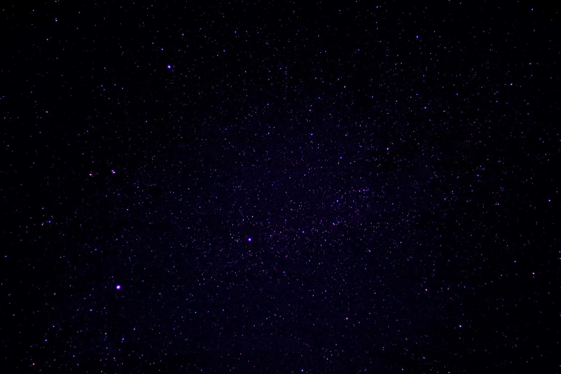 A quiet purple-black sky with widely spaced stars, one brighter point sitting low on the left and the rest fading toward the corners.