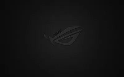 The ROG eye sits centre-frame only a shade lighter than the near-black ground, so the logo all but disappears until the screen brightens.
