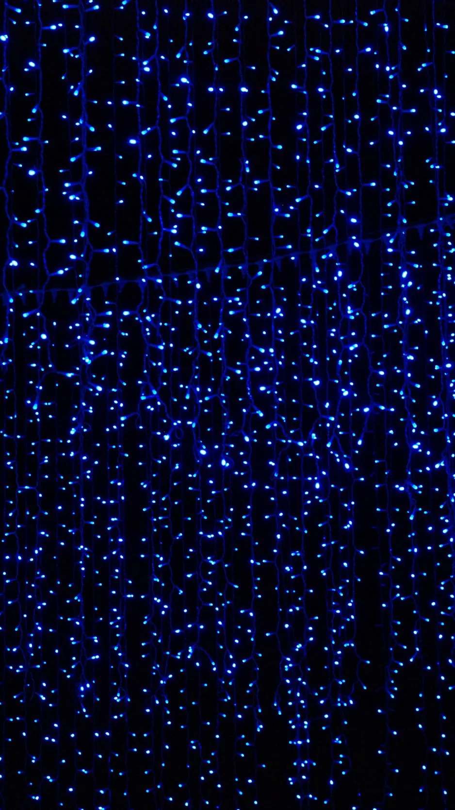 Hundreds of tiny blue fairy lights hang in vertical strands against darkness, dense enough that icons stay readable anywhere on the screen.