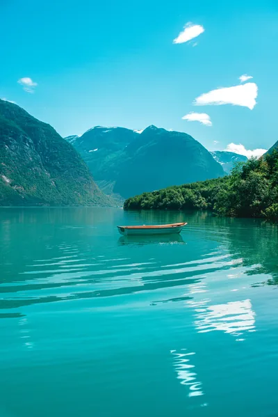 Still turquoise water surrounds a lone wooden boat mid-frame; the lower half of this portrait is nearly featureless, ideal ground for a lock-screen clock or app grid.