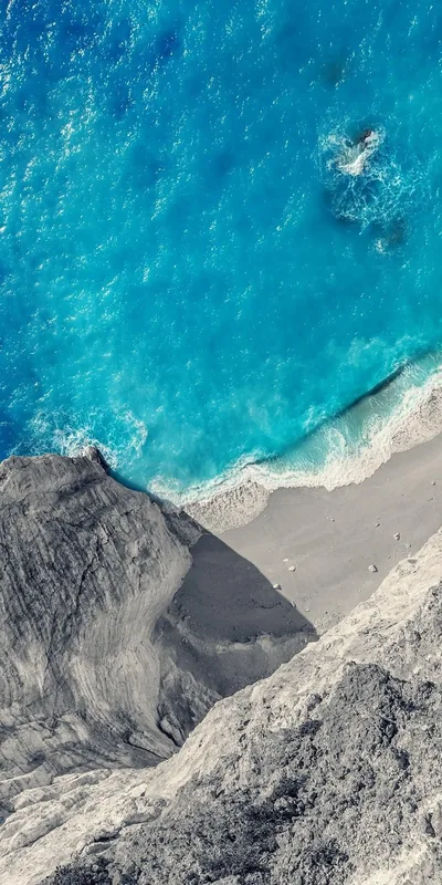 Bright Blue Water Against Grey Cliffs HD Phone Wallpaper