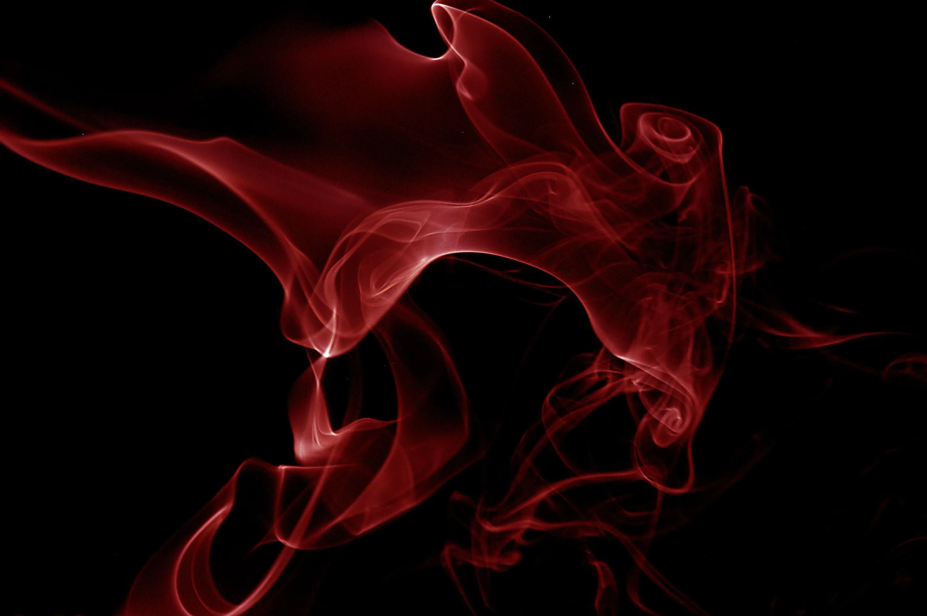 Ribbons of deep red fold over themselves in the centre like silk caught mid-air, surrounded on all sides by unbroken black.