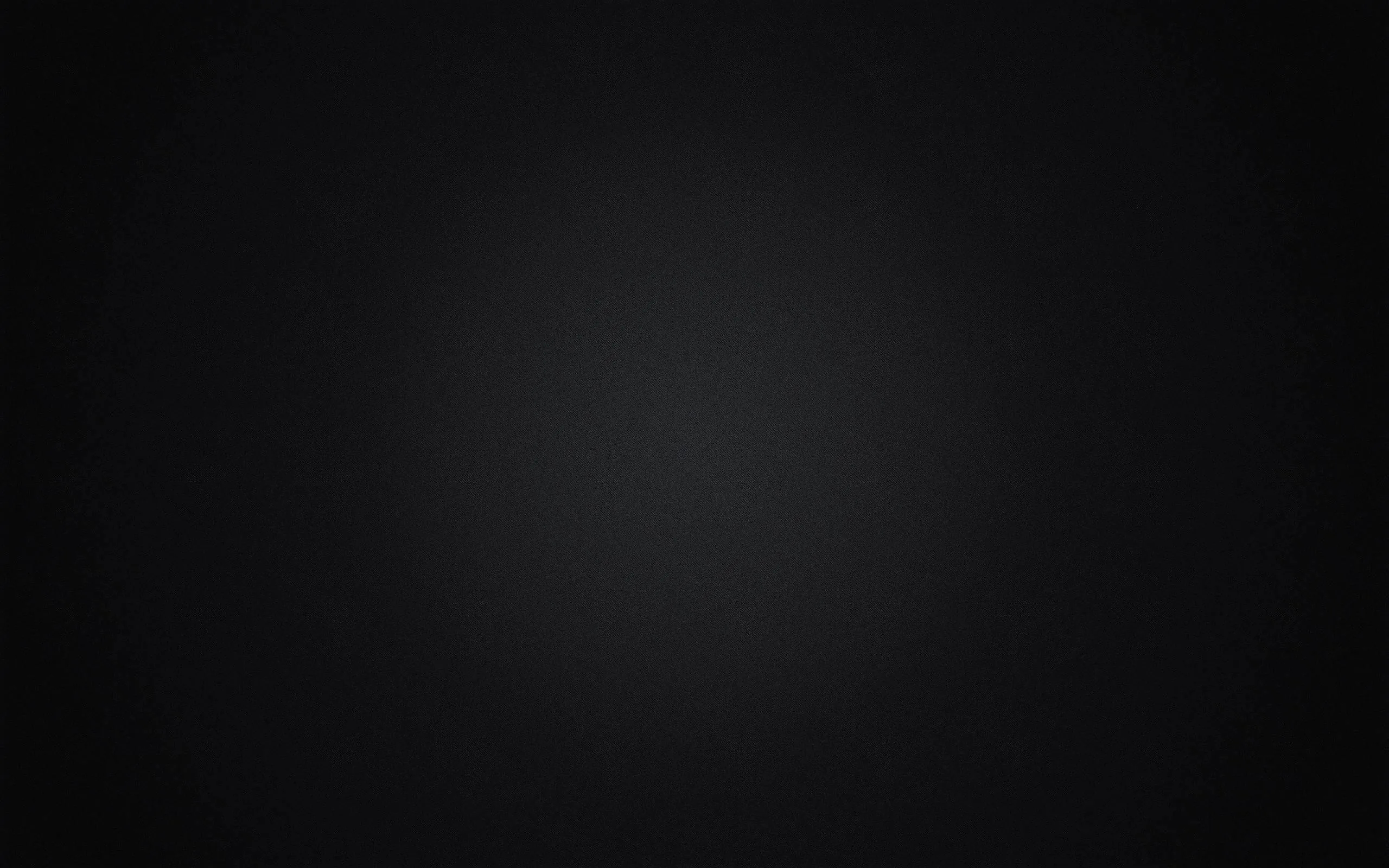 A soft grey light pools slightly above centre and falls away in every direction, leaving all four corners in full black.