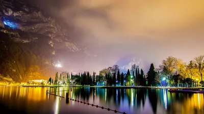 Beautiful View Of Trees Lights Reflection On Water Mountains Background